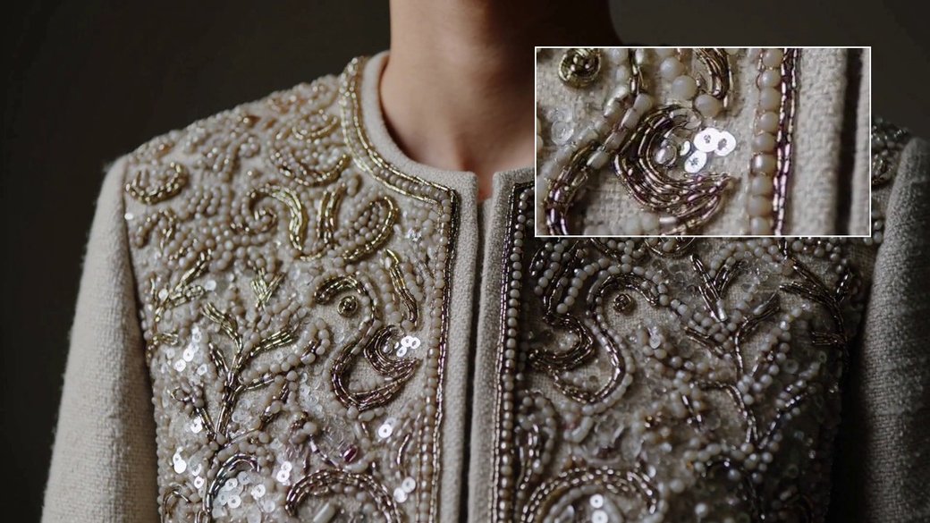 Close detail of hand-beaded embroidery on a cream jacket